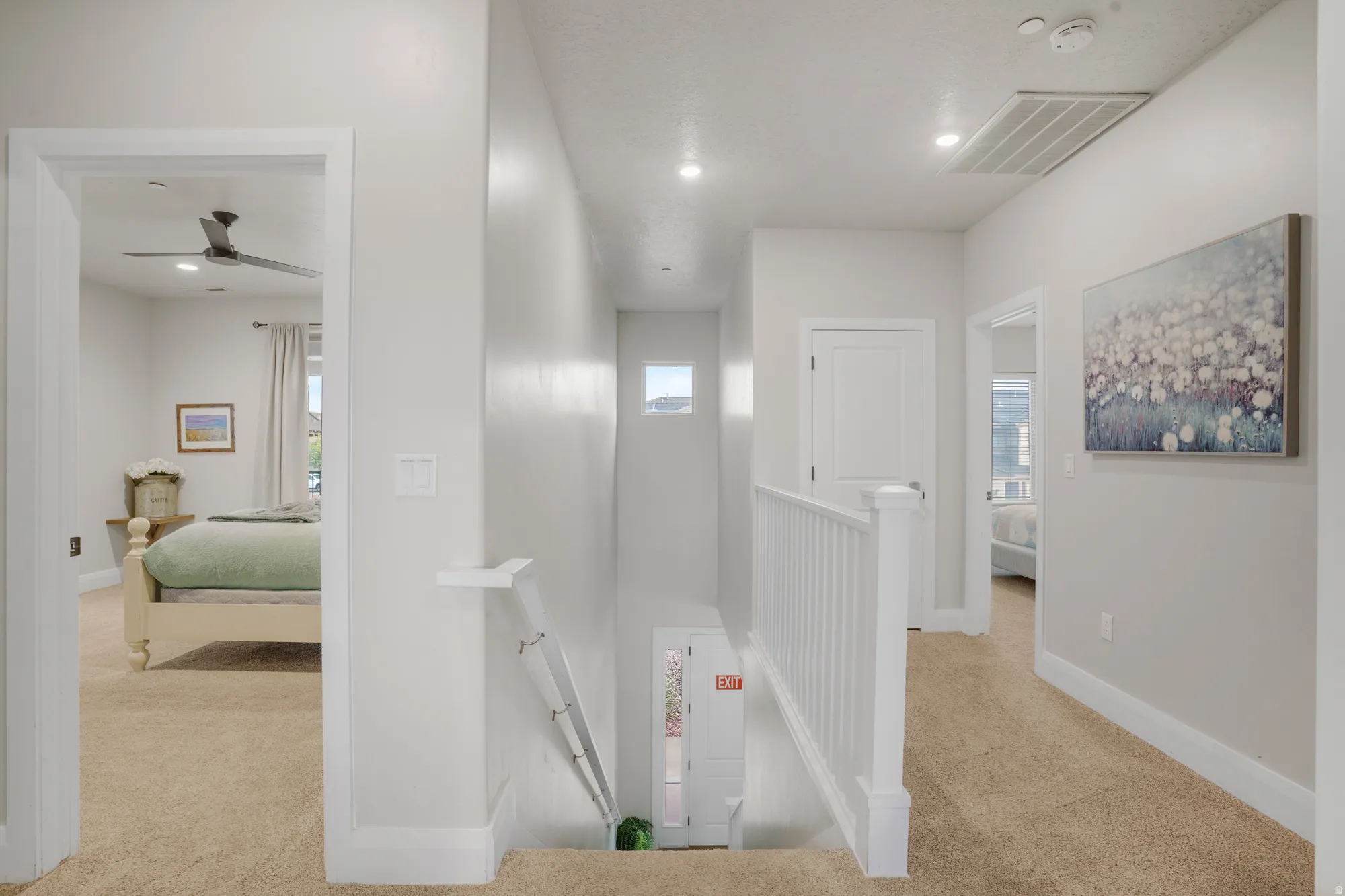 Upper-level hallway with carpeted flooring and white painted walls