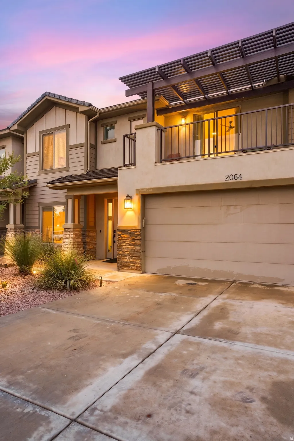 Contemporary exterior featuring a private balcony with a slatted pergola, attached garage, and stone accent columns