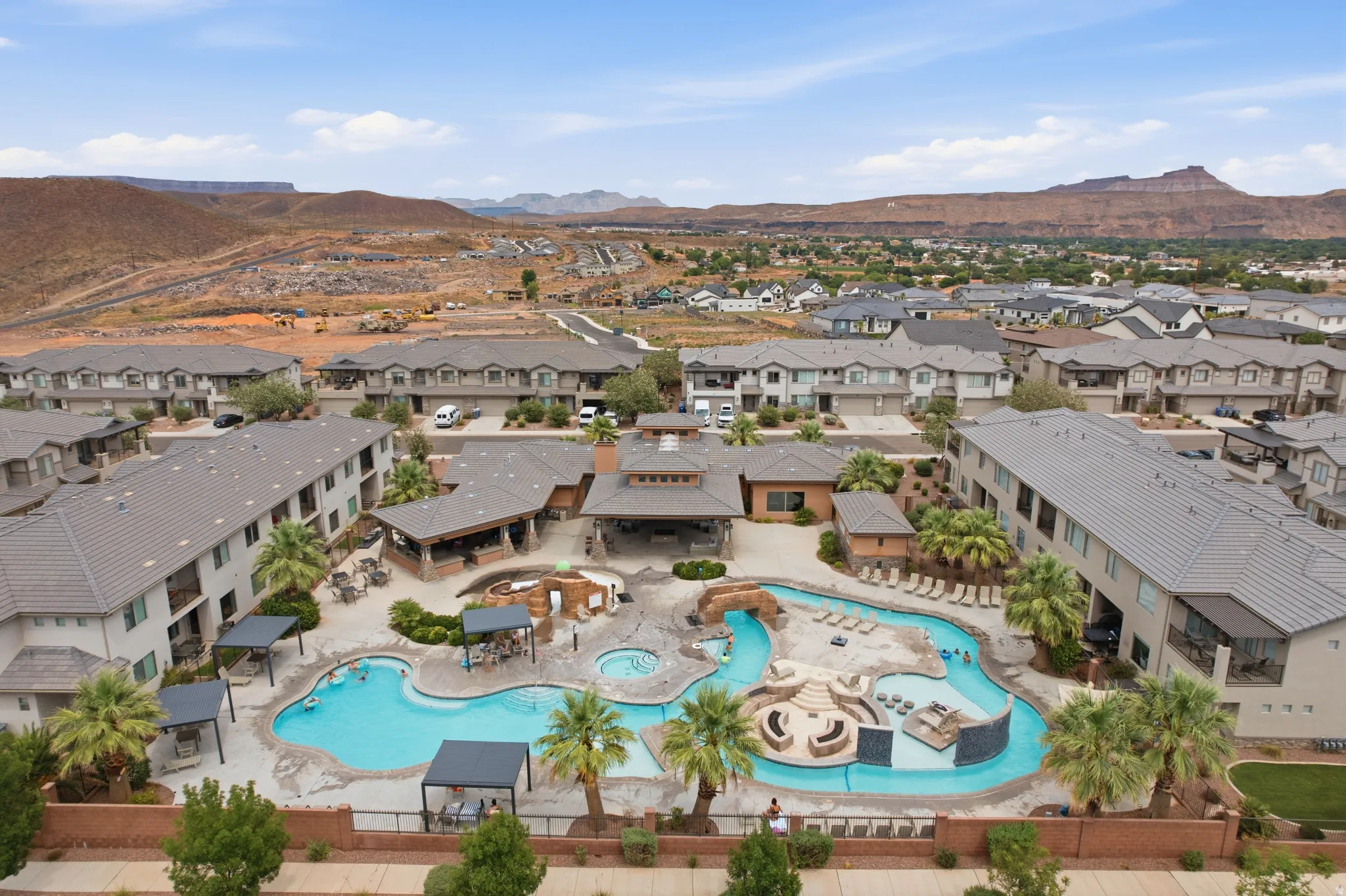 Expansive outdoor aquatic area featuring a large swimming pool, a separate spa, and a winding lazy river