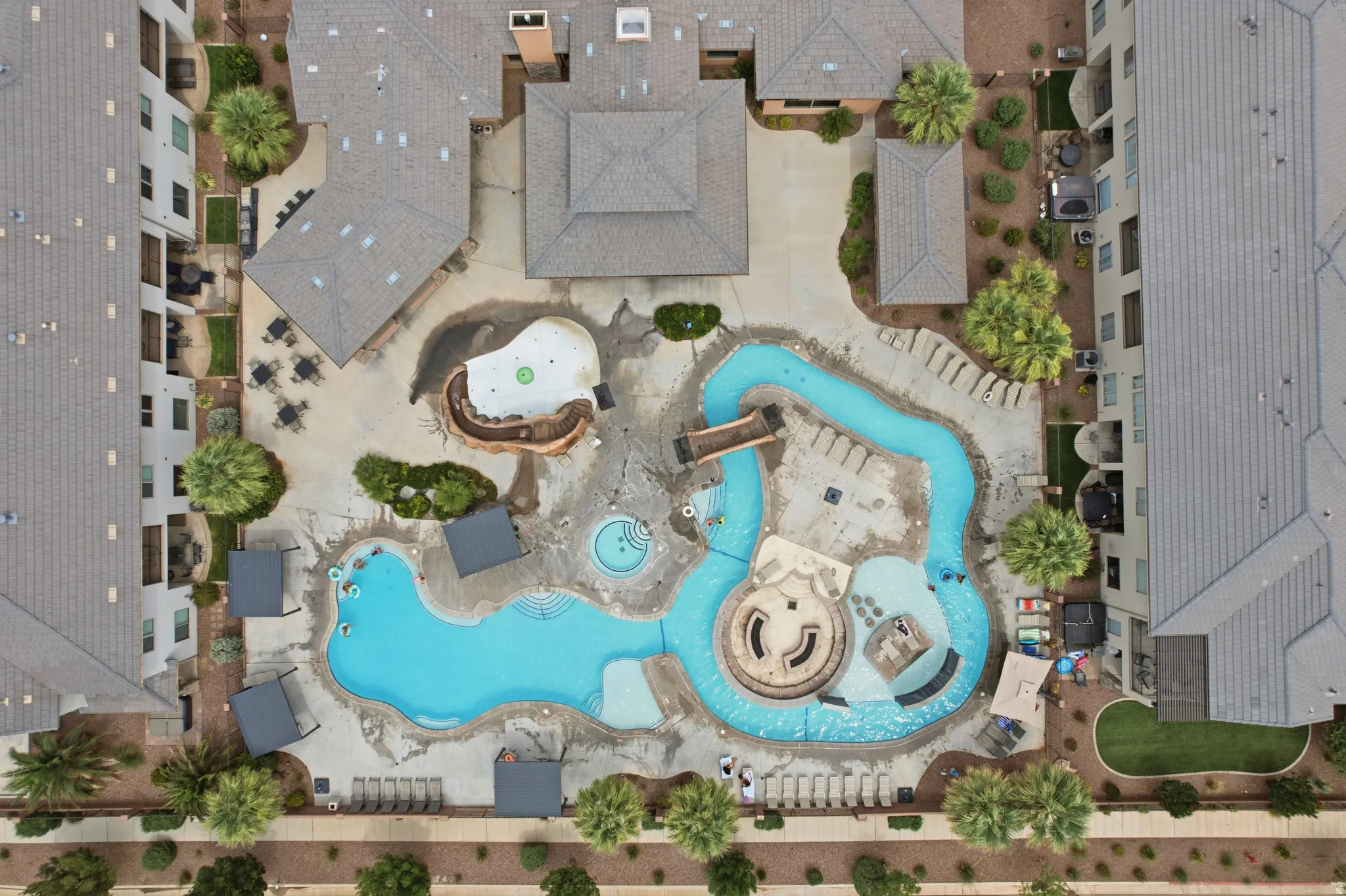 Resort-style pool area featuring a lazy river, multiple swimming zones, a spa, and shaded cabanas