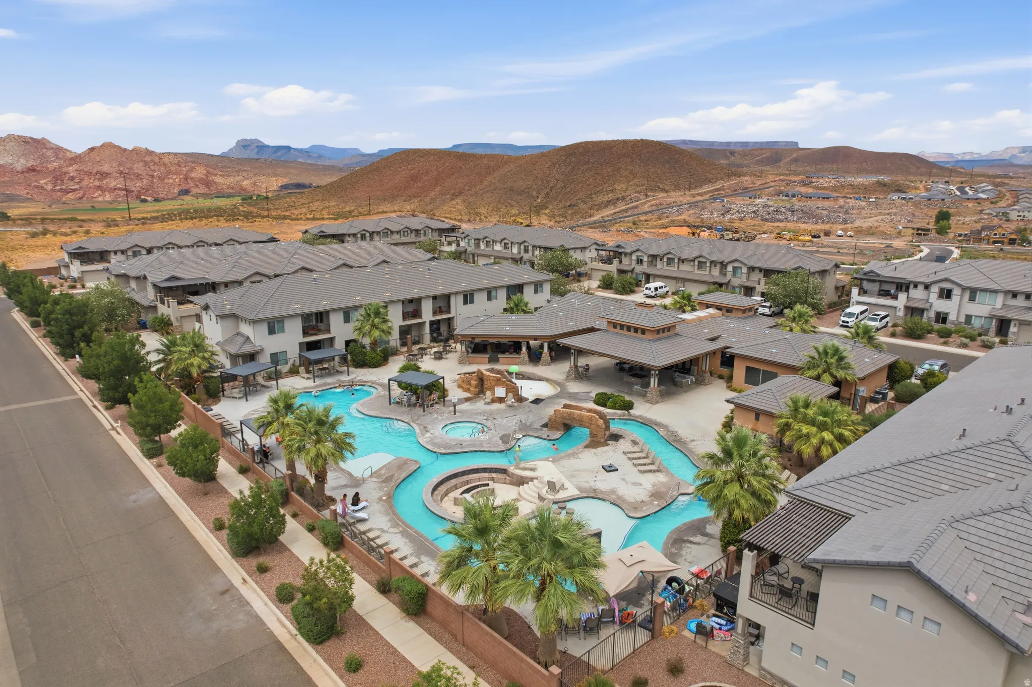 Community swimming pool with a curved design, integrated spa, and a rock-feature bridge