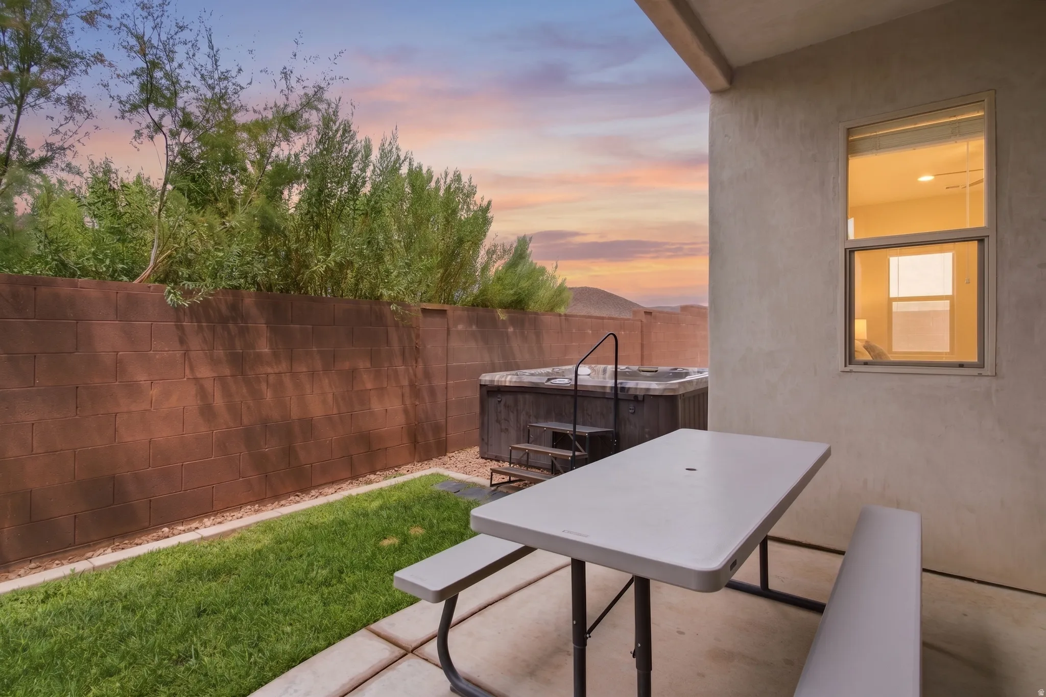Private backyard featuring a built-in hot tub with steps, a concrete patio, a manicured lawn, and a block perimeter wall