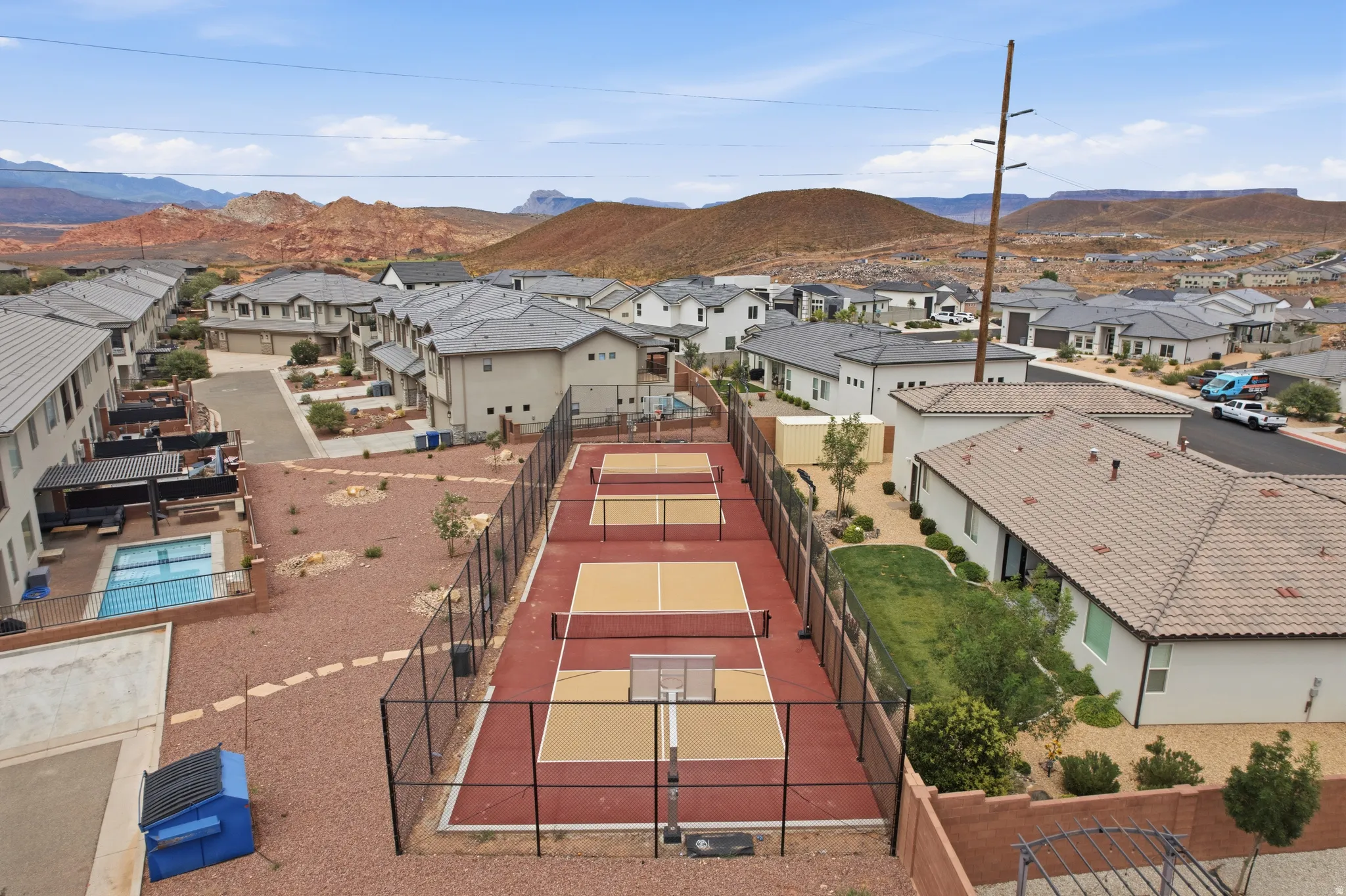 Community sports courts with red and tan surfacing, surrounded by black fencing