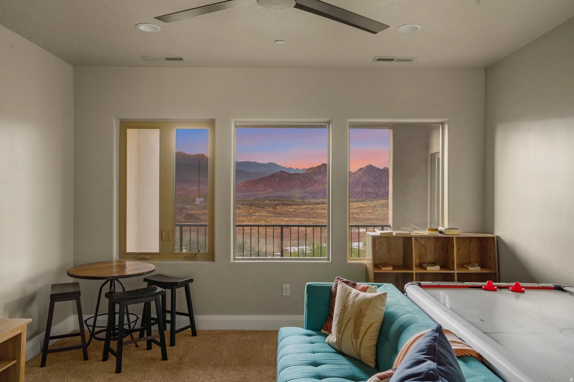 Room with mountain scenery through multiple windows, ceiling fan, and recessed lighting