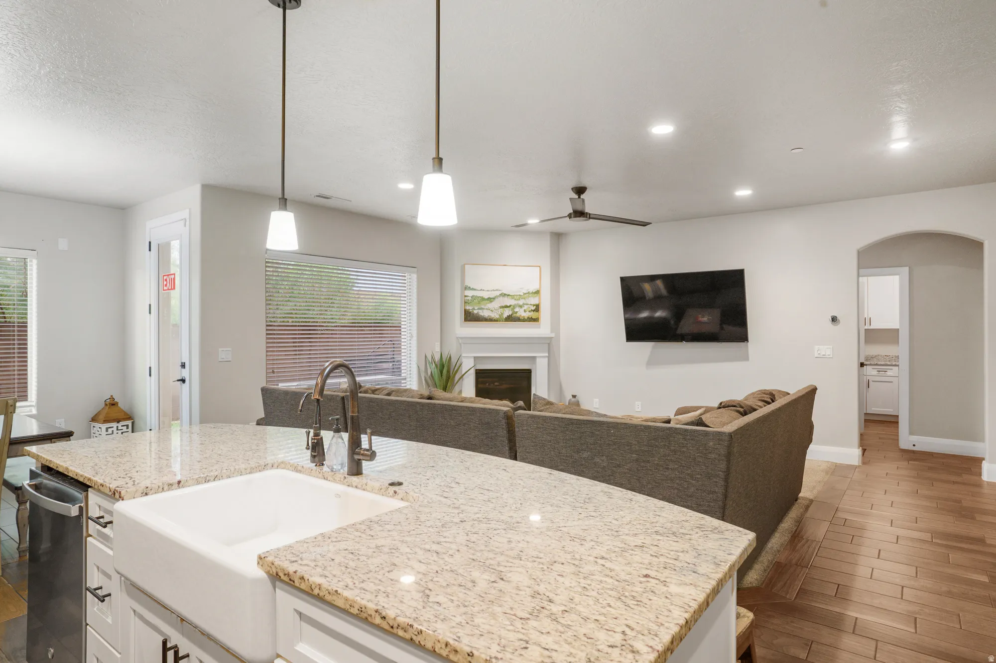 Kitchen island with a farmhouse sink, granite countertops, and pendant lighting
