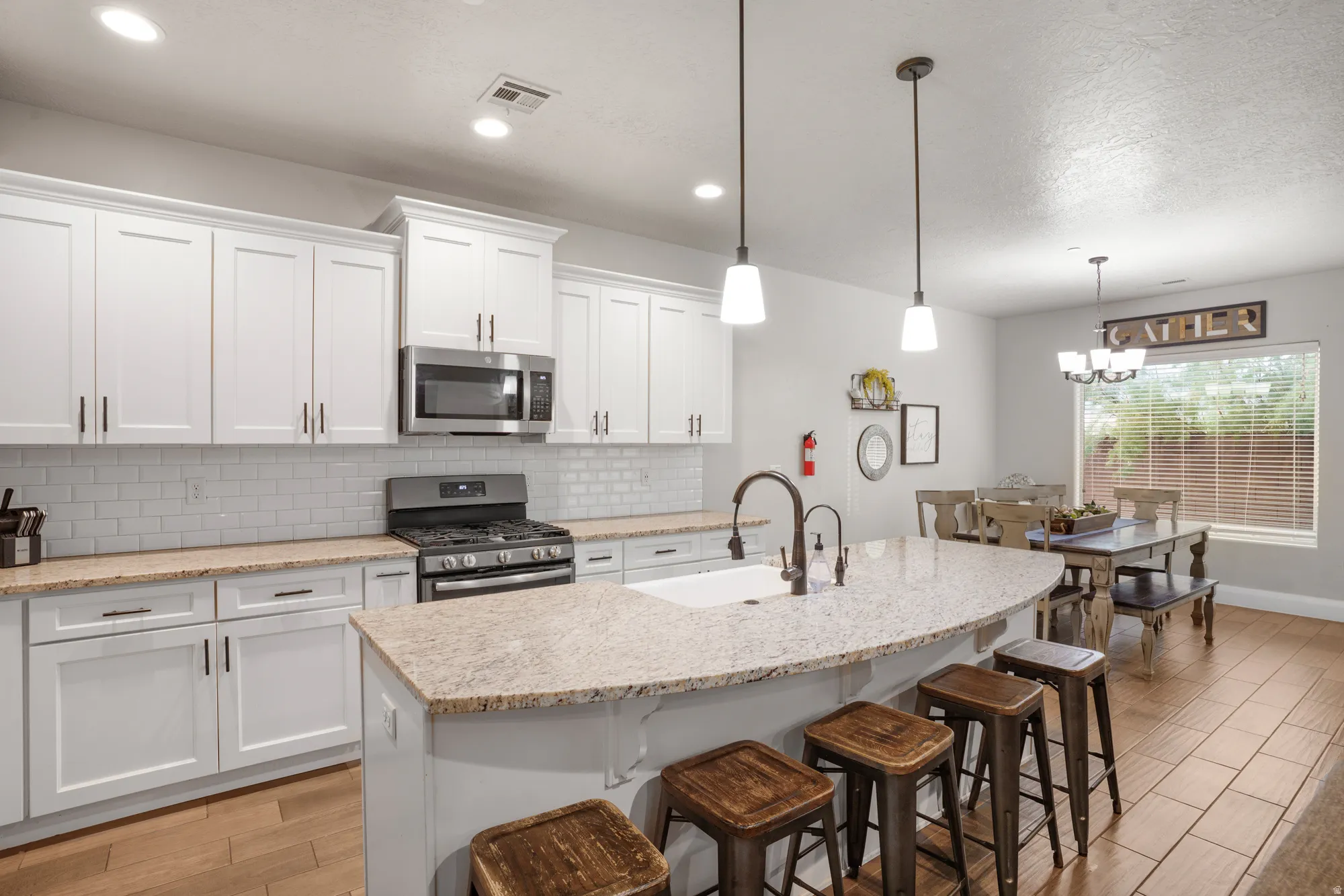 Kitchen featuring a large island with a composite countertop, white shaker cabinetry, stainless steel appliances, and wood-finish flooring
