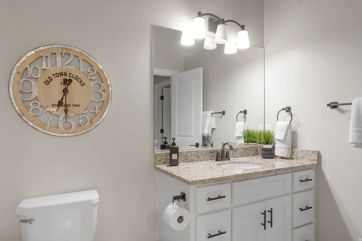 Bathroom featuring a light-colored vanity with a granite countertop and an undermount sink