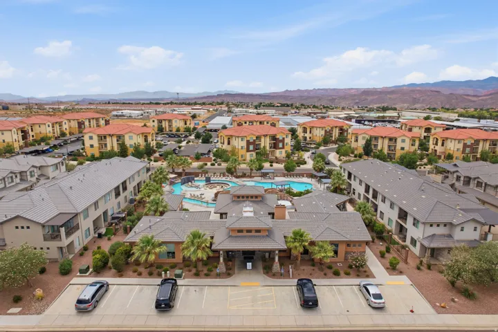 Expansive community featuring multiple residential buildings with tile roofs, a central clubhouse, and a resort-style swimming pool area with integrated spa