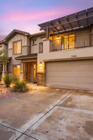 Contemporary exterior featuring a private balcony with a slatted pergola, attached garage, and stone accent columns