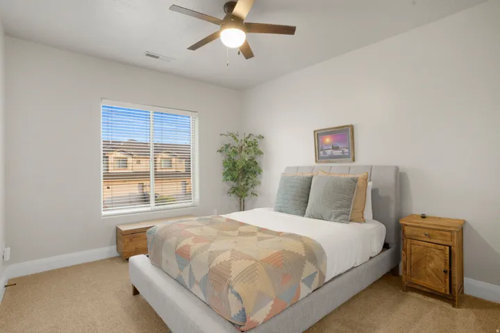 Bedroom featuring neutral wall paint, carpet flooring, a window with horizontal blinds, a ceiling fan with integrated lighting, and white baseboards