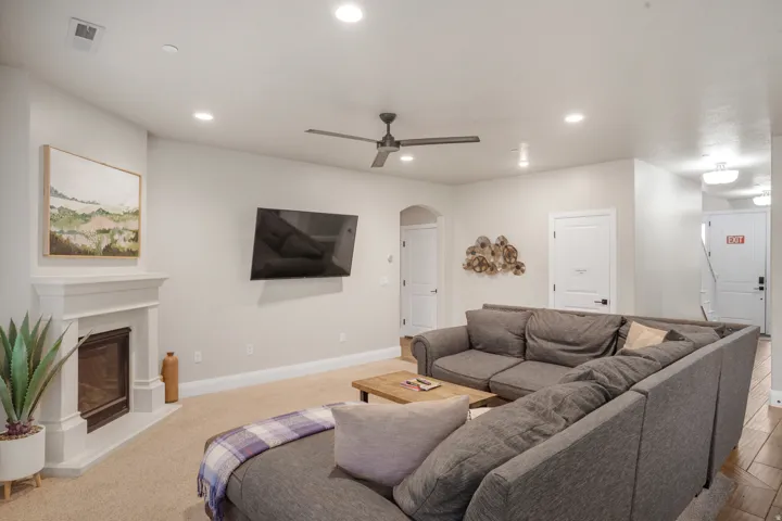 Living area featuring a fireplace with a white mantel, recessed lighting, and a ceiling fan