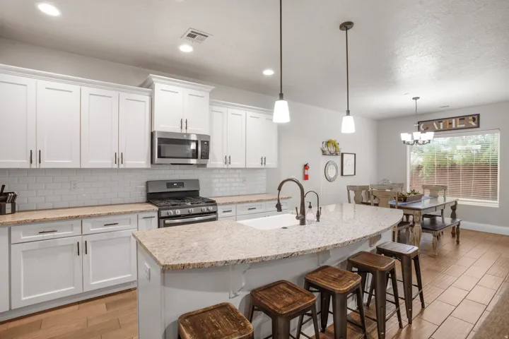 Kitchen featuring a large island with a composite countertop, white shaker cabinetry, stainless steel appliances, and wood-finish flooring