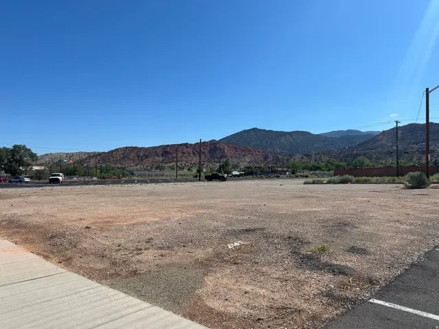 Expansive undeveloped lot featuring a gravel and dirt surface, mountain backdrop, and clear sky