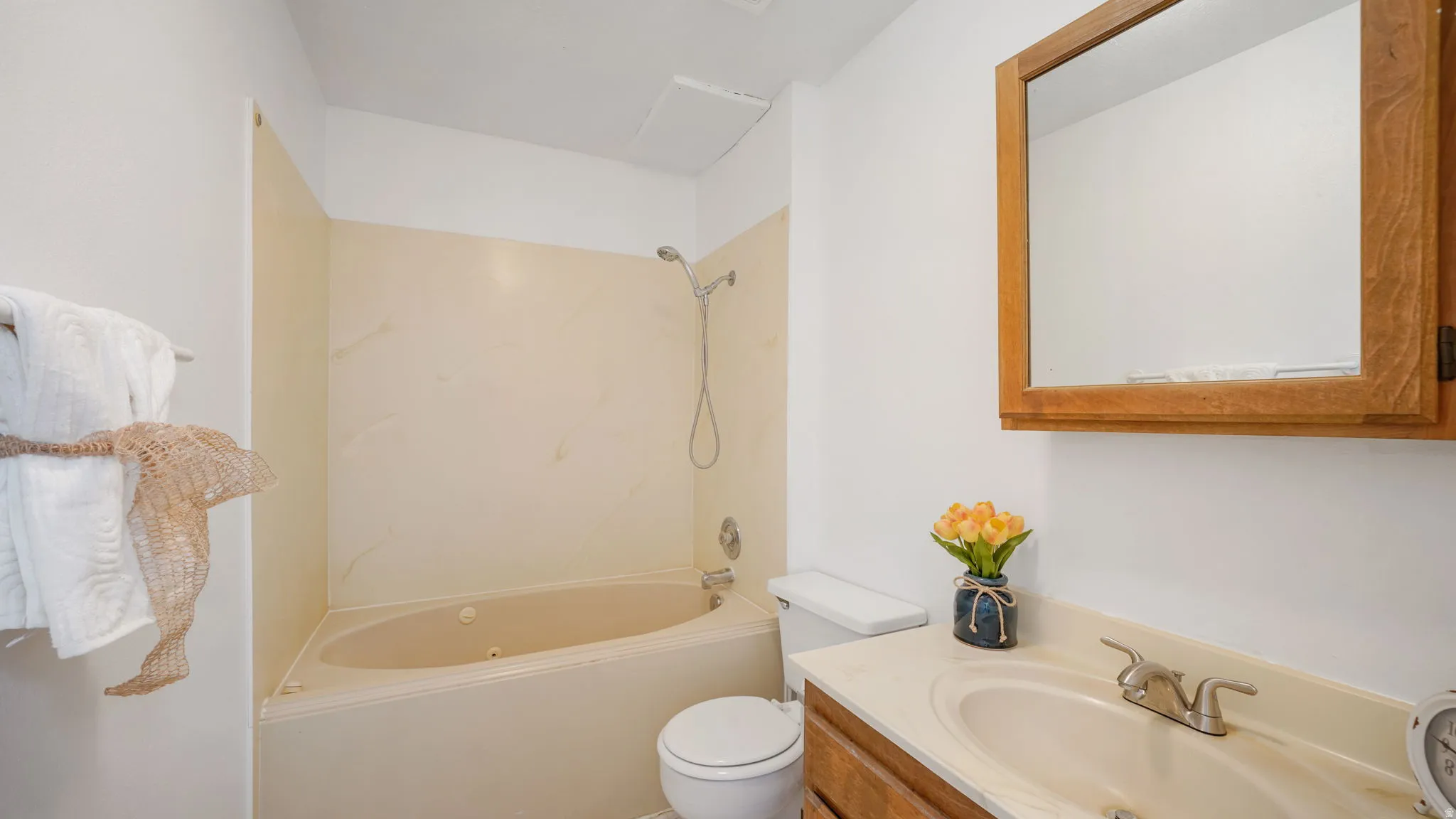 Bathroom featuring a built-in tub with shower, wood-finish vanity with an integrated sink, and an overhead medicine cabinet with a wood-finish frame