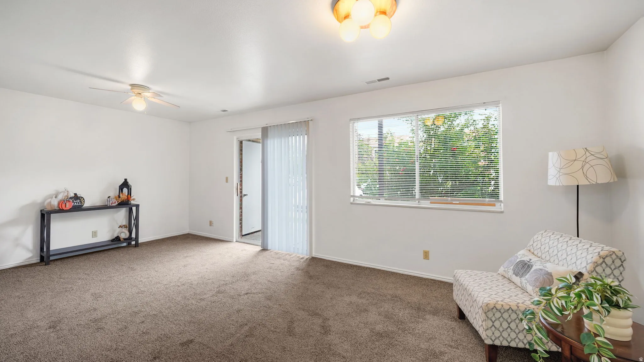 Expansive room featuring neutral-toned carpeting, a ceiling fan, and a flush mount light fixture