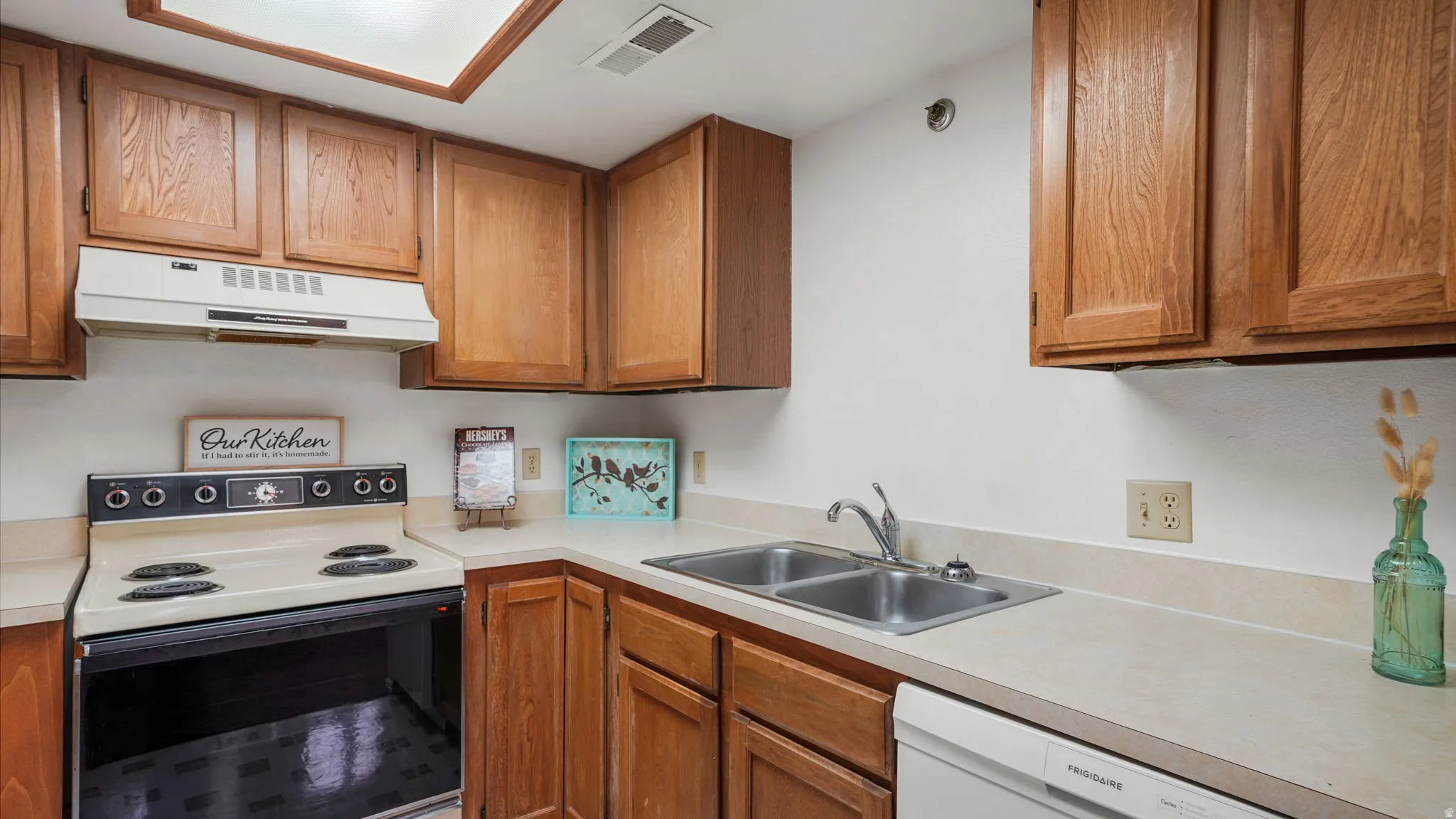 Kitchen featuring wood cabinetry, a double basin stainless steel sink, and a built-in dishwasher