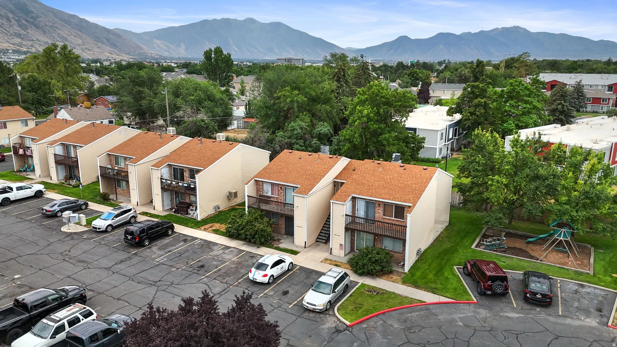 Multi-unit residential buildings with parking lot and an adjacent green-space with playground equipment