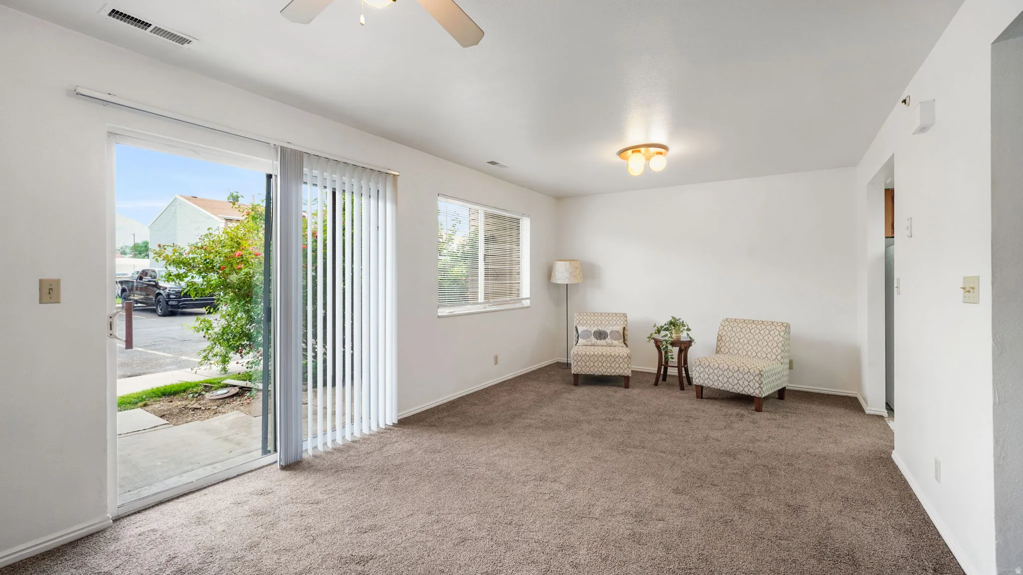 Living area featuring a sliding glass door, overhead lighting, window with blinds, and carpeted flooring