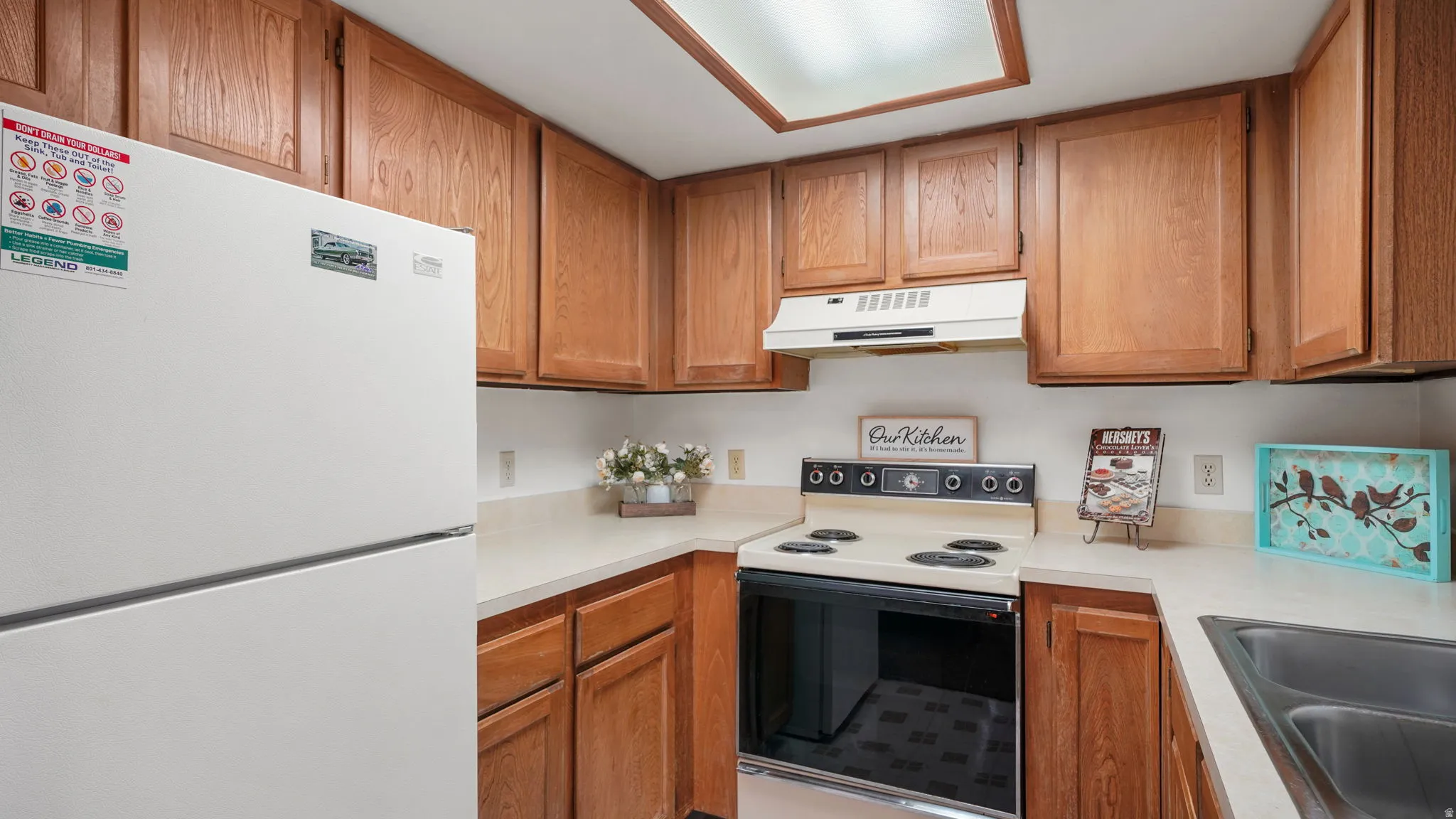 Kitchen featuring wood-finish cabinetry, white countertops, and a full suite of appliances including a range, refrigerator and dishwasher