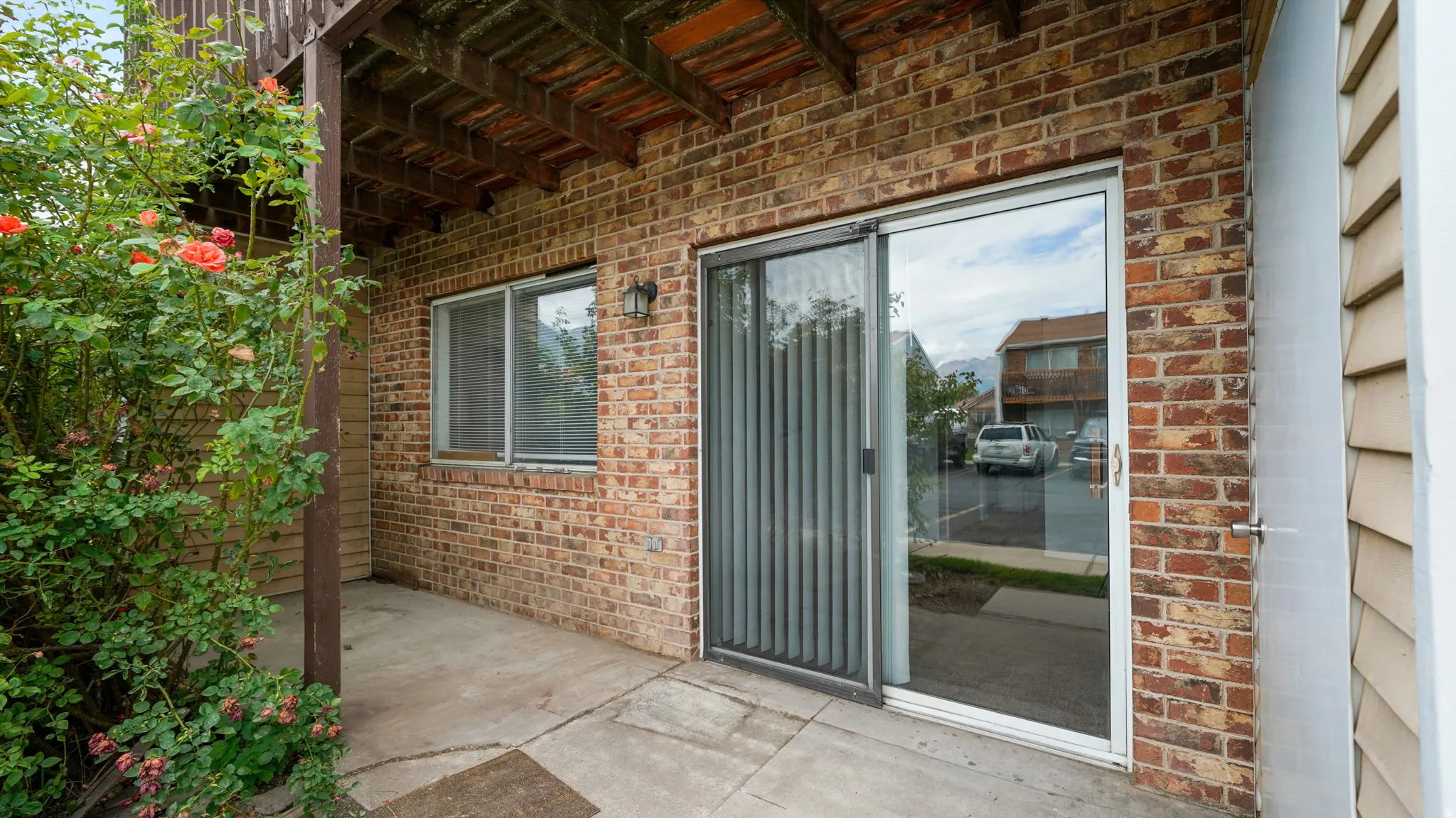 Brick exterior with a covered patio, featuring a sliding glass door and an exterior light fixture