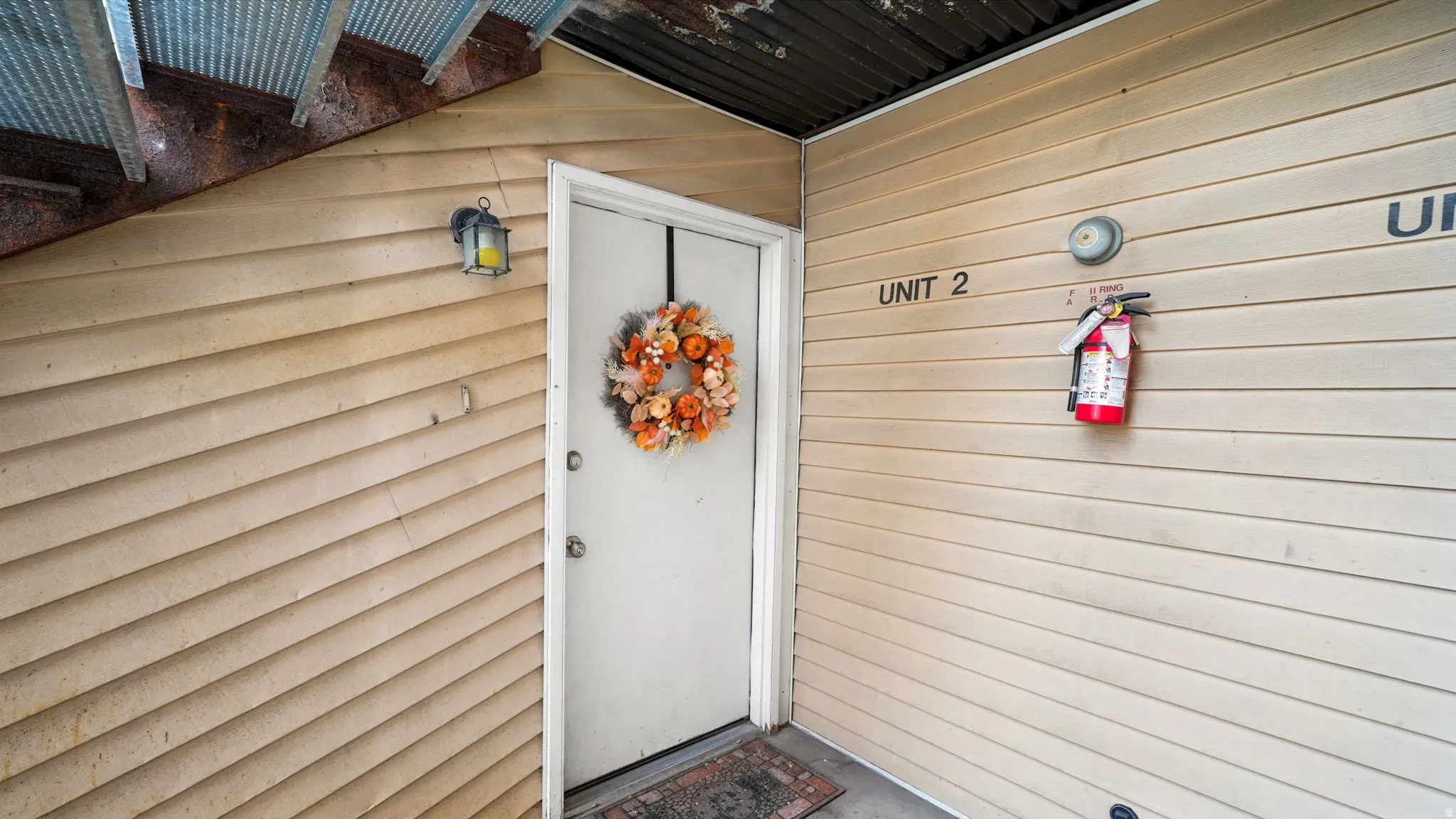 Unit #2 No step entry door with white trim, tan siding