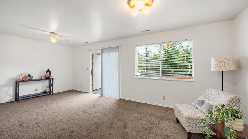 Expansive room featuring neutral-toned carpeting, a ceiling fan, and a flush mount light fixture