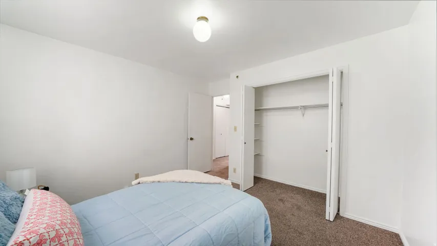 Bedroom #1 featuring neutral wall paint, a built-in closet with bifold doors, and a ceiling-mounted light fixture