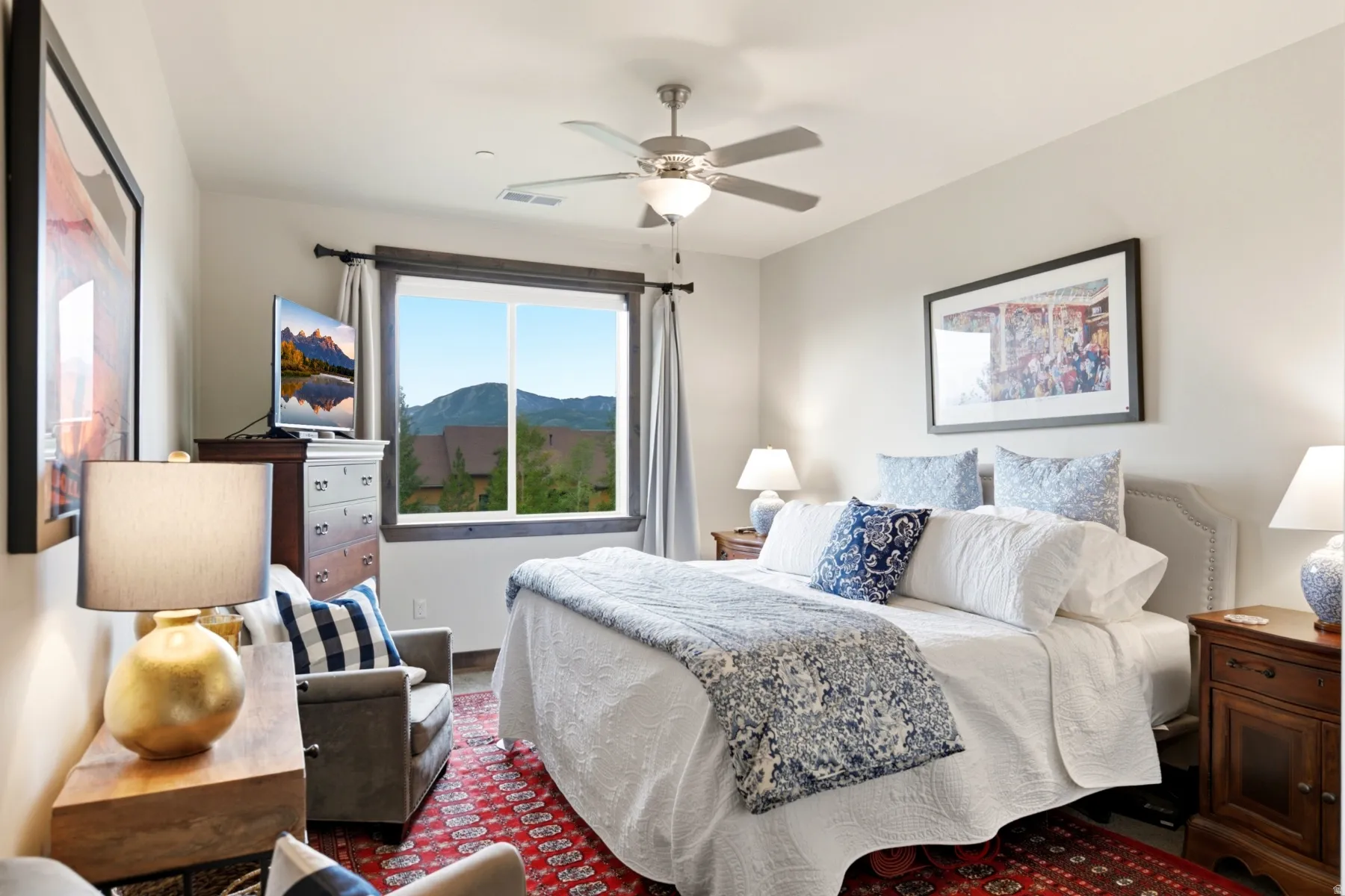 Bedroom featuring a large window with mountain scenery, a ceiling fan, a fabric headboard, and wood-finish flooring