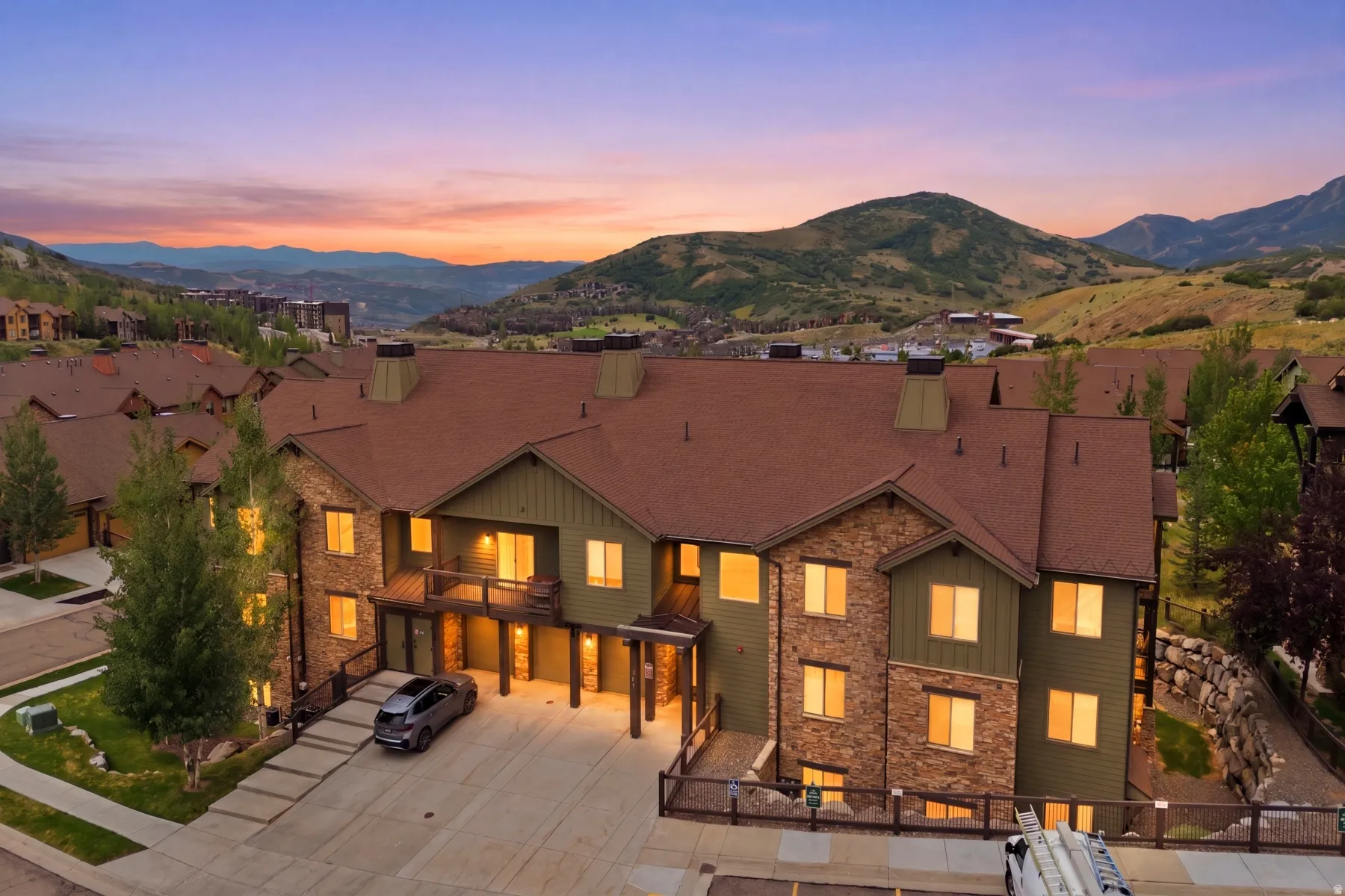 Multi-level property with stone and siding exterior, multiple balconies, and a mountain backdrop
