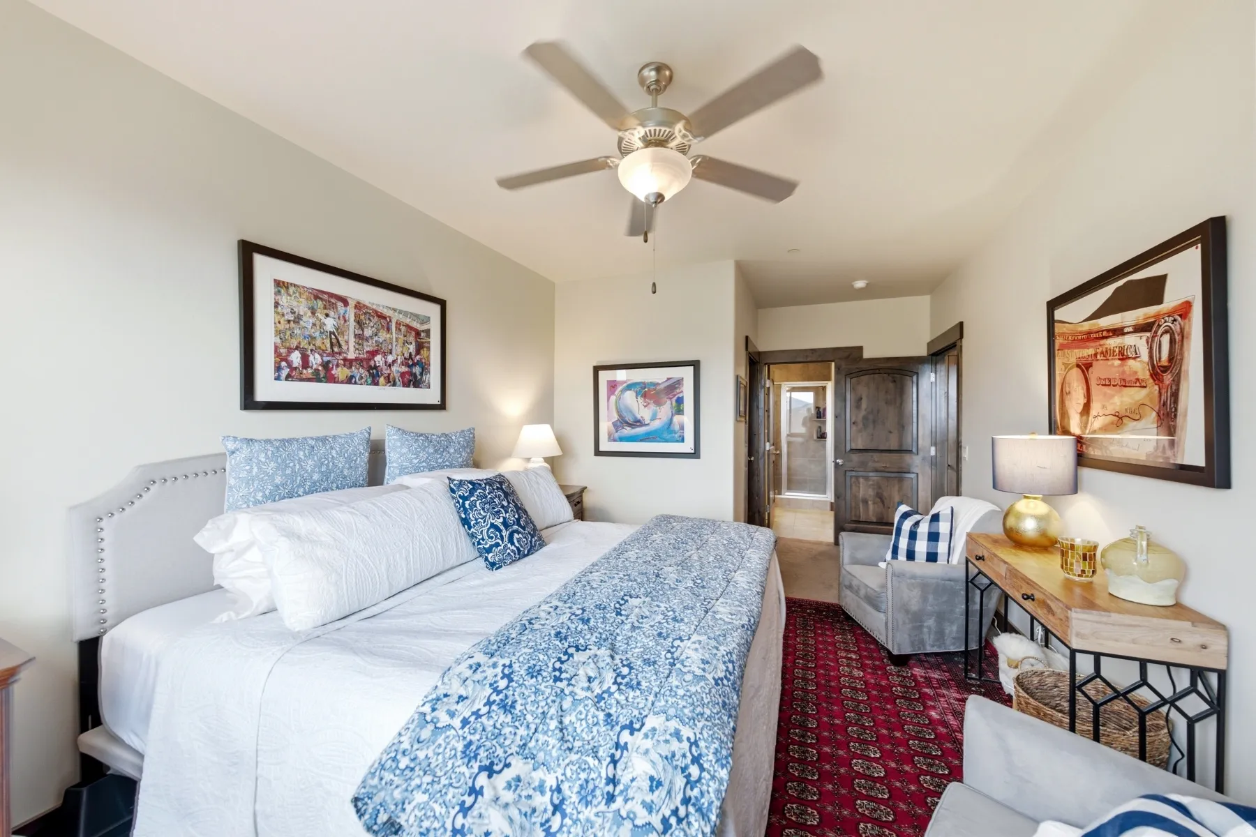 Spacious bedroom featuring light-toned walls, a ceiling fan, and dark wood-finish interior doors