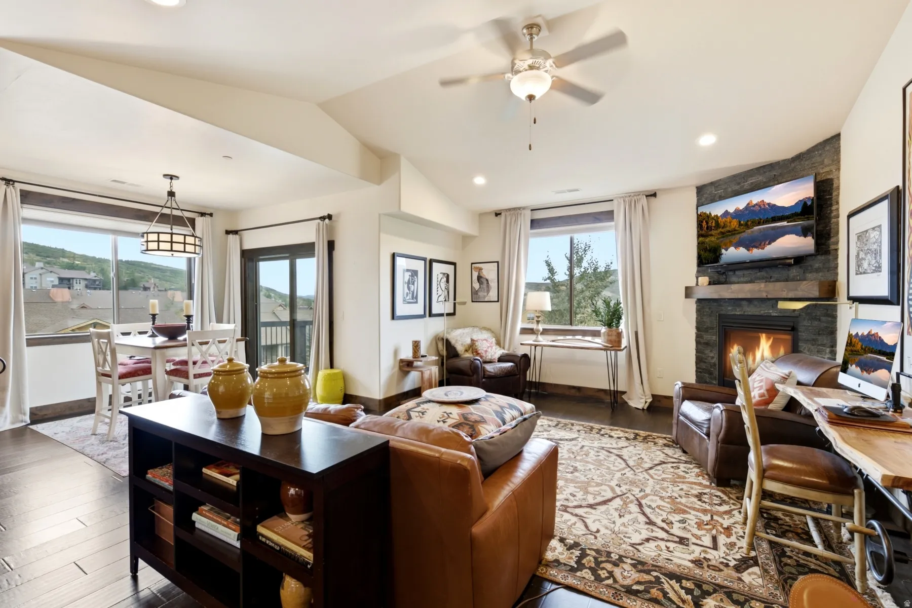 Spacious living area featuring a corner gas fireplace with stone surround, wood mantle, and television mount
