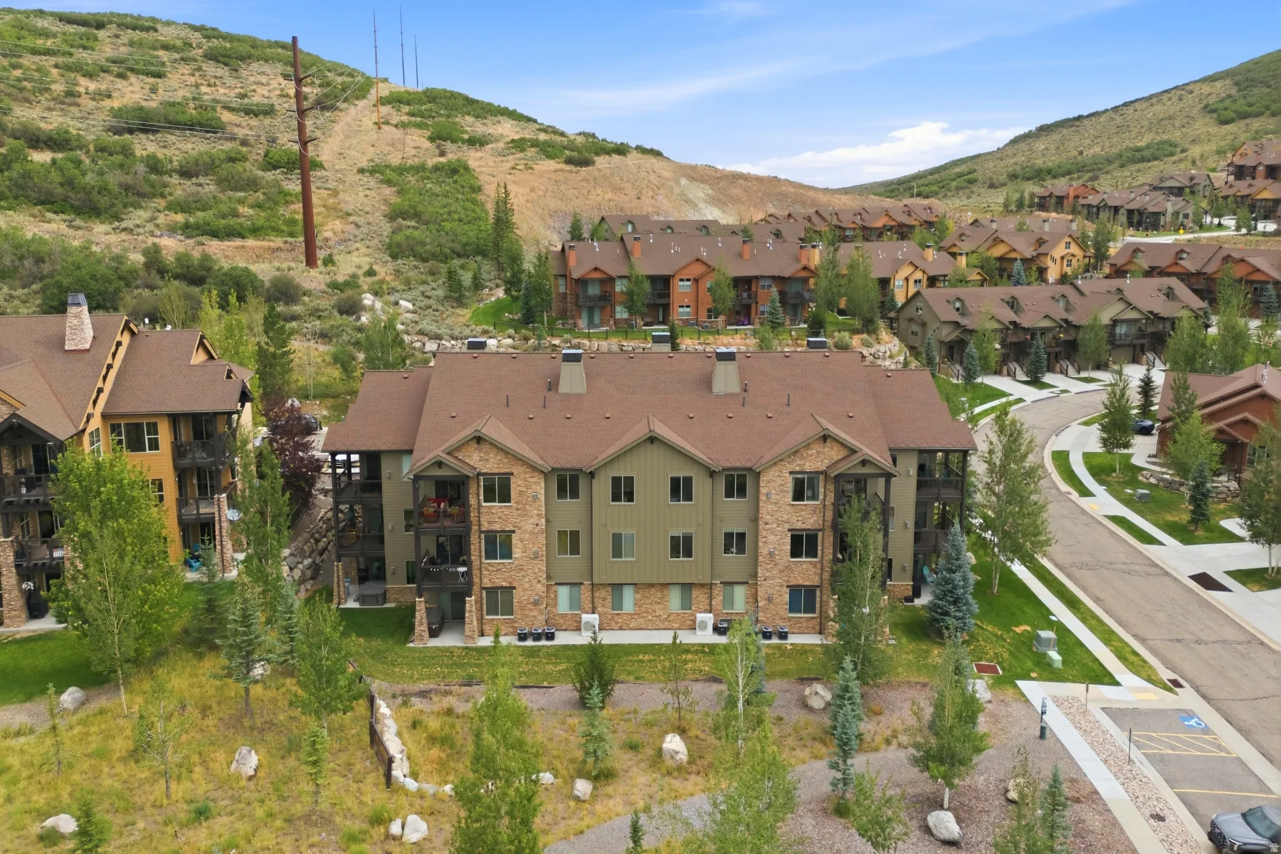 Multi-story residential building featuring a stone and siding exterior, multiple balconies, and a brown shingle roof