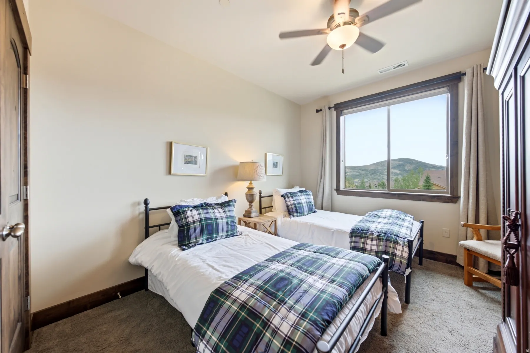 Bedroom featuring a large window, a ceiling fan with integrated lighting, wood-finish baseboards, and a dark wood-finish door