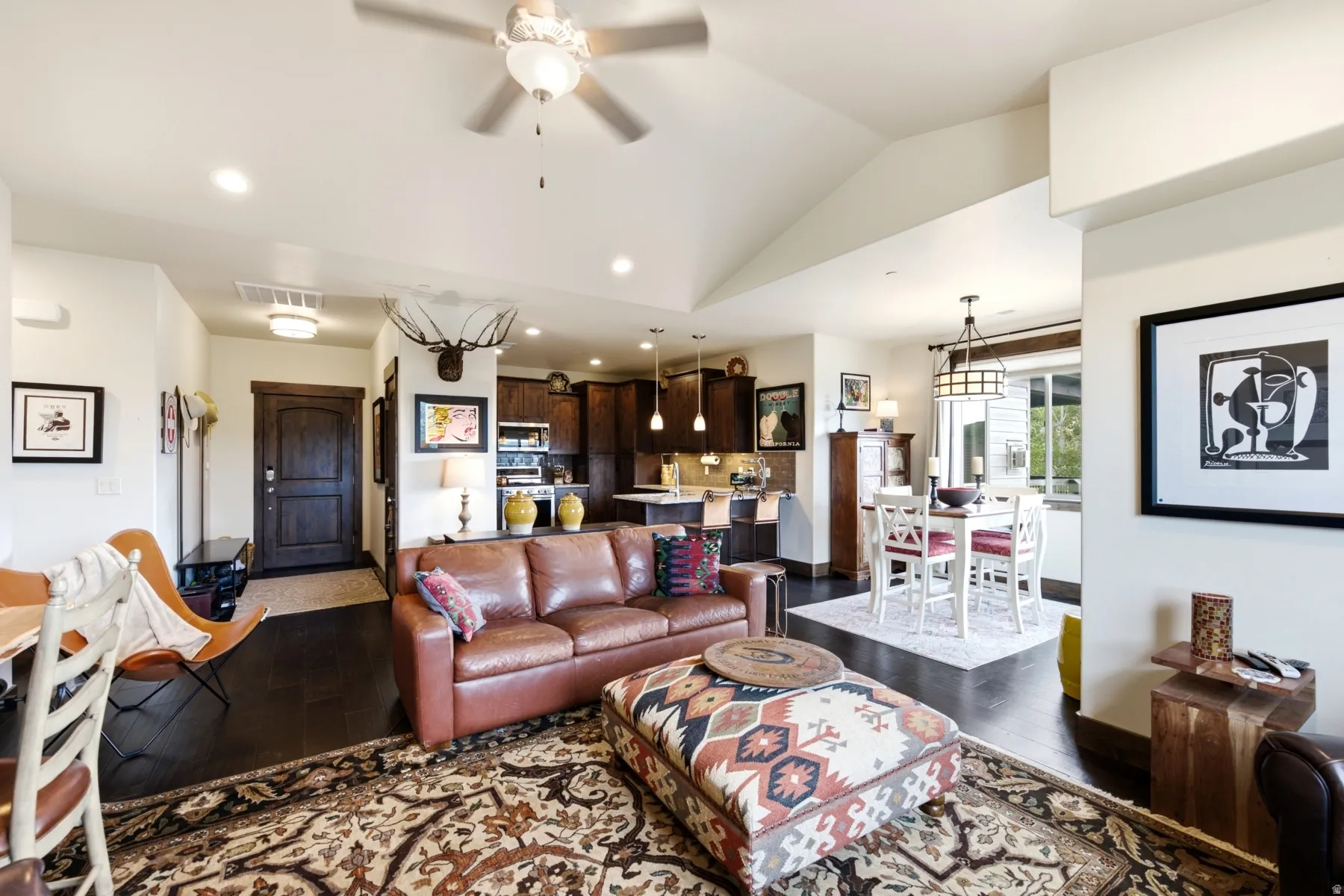 Open-concept living area featuring vaulted ceilings, dark wood-finish flooring, recessed lighting, and a ceiling fan