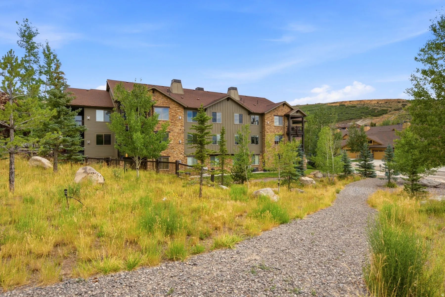 Multi-story residential building featuring stone and siding exterior, multiple windows, and balconies