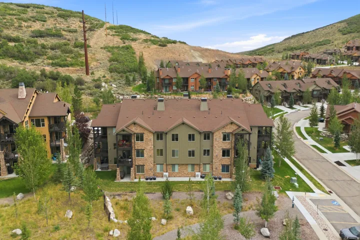 Multi-story residential building featuring a stone and siding exterior, multiple balconies, and a brown shingle roof