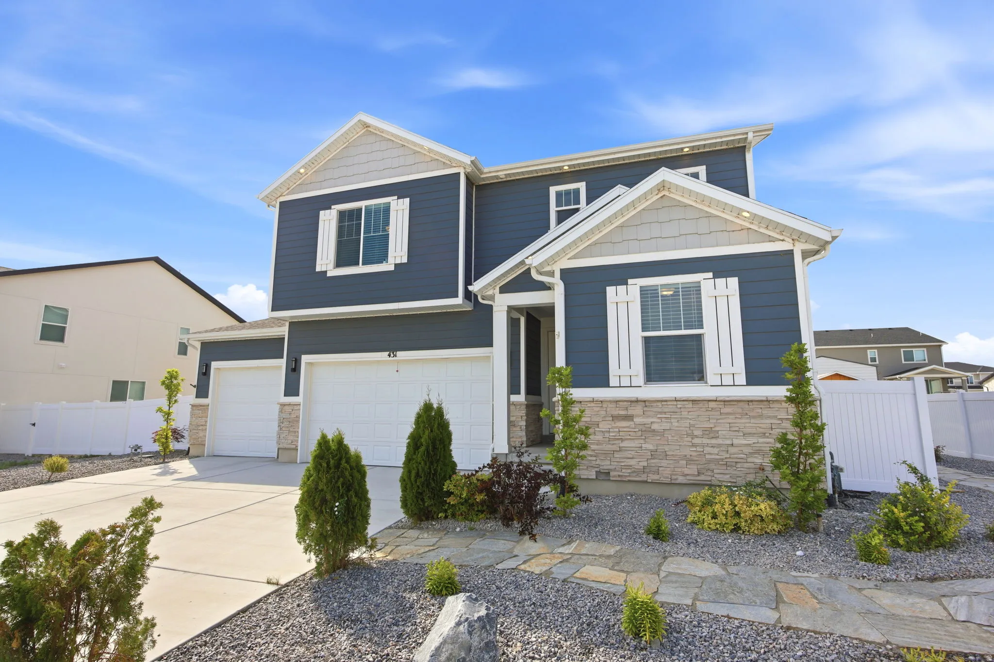 Contemporary two-story residence featuring a blue siding exterior with stone veneer accents and white trim