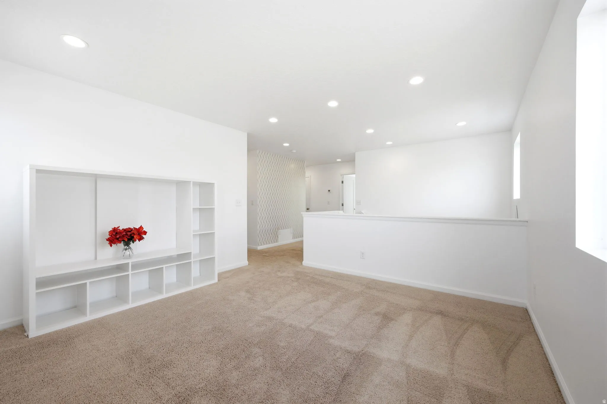 Spacious open room featuring recessed lighting, light-toned carpeting, and a built-in media console with shelving