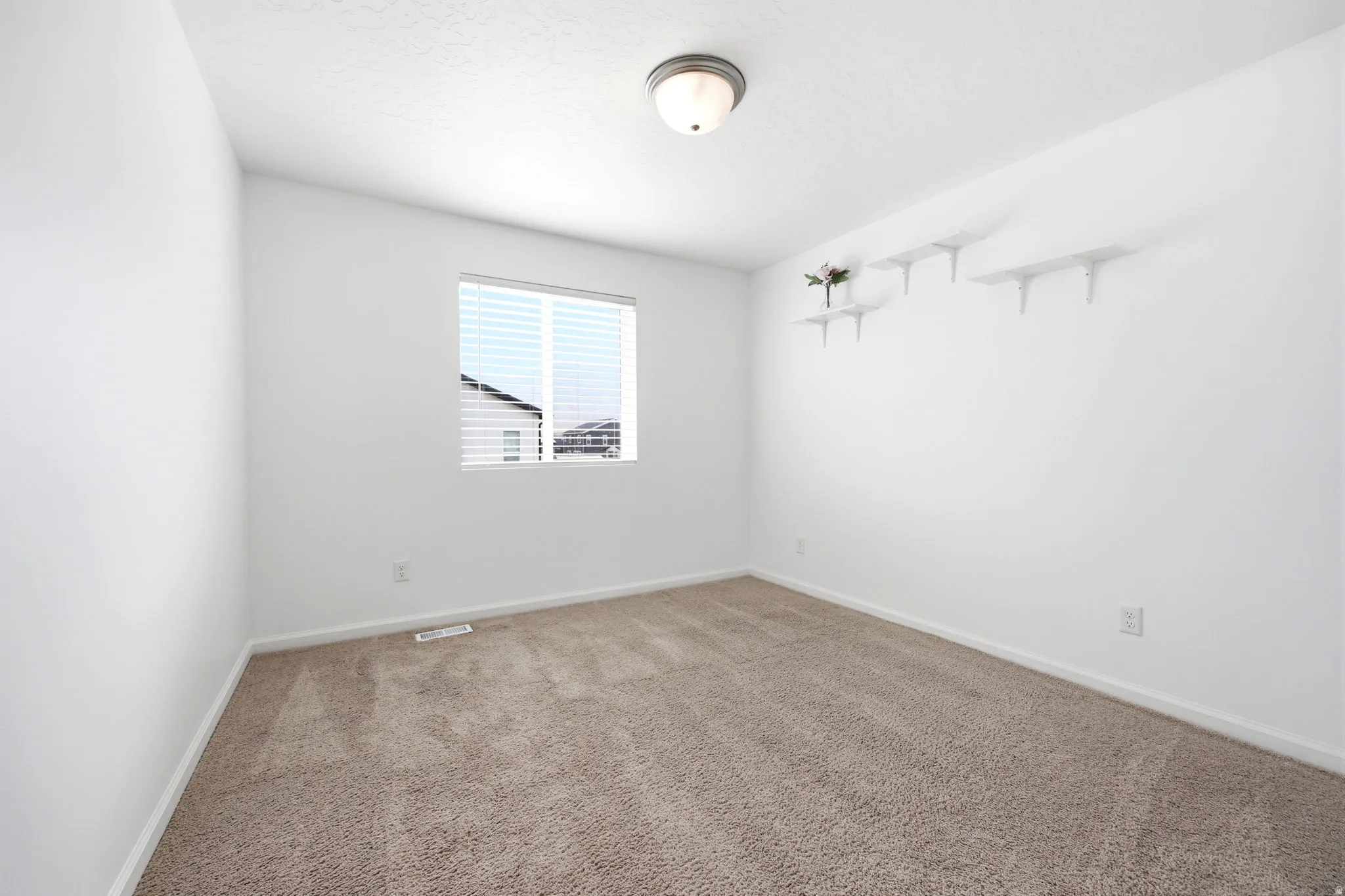 Interior room featuring neutral carpeting, white walls, and a single window with blinds