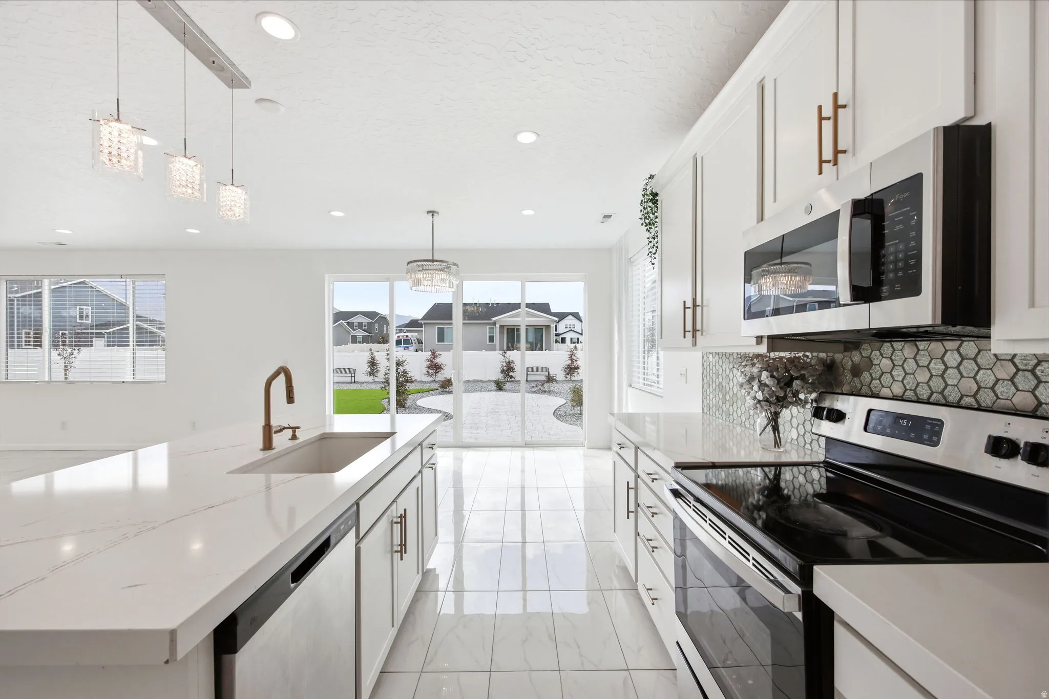 Open-concept kitchen featuring white cabinetry, quartz countertops, and stainless steel appliances