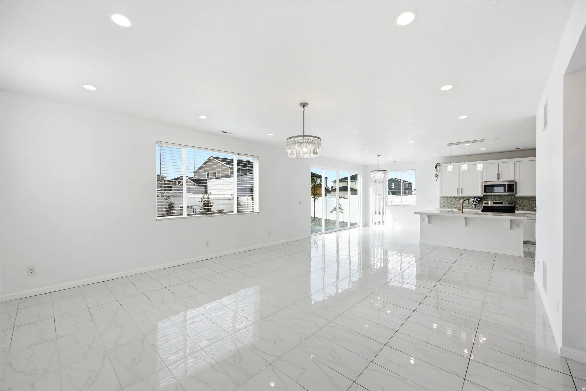 Open-concept living space featuring large format white tile flooring, recessed lighting, and a modern chandelier