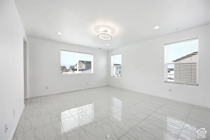 Bright room featuring large format white tile flooring with grey veining, three windows with horizontal blinds, a modern ceiling light fixture, and recessed lighting