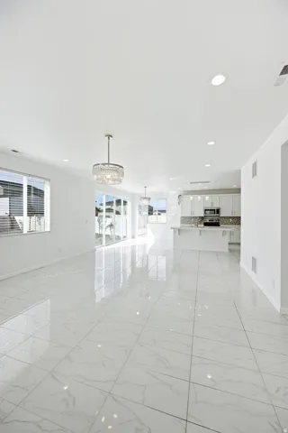 Expansive open-concept living area featuring large format tile flooring, recessed lighting, and a contemporary chandelier
