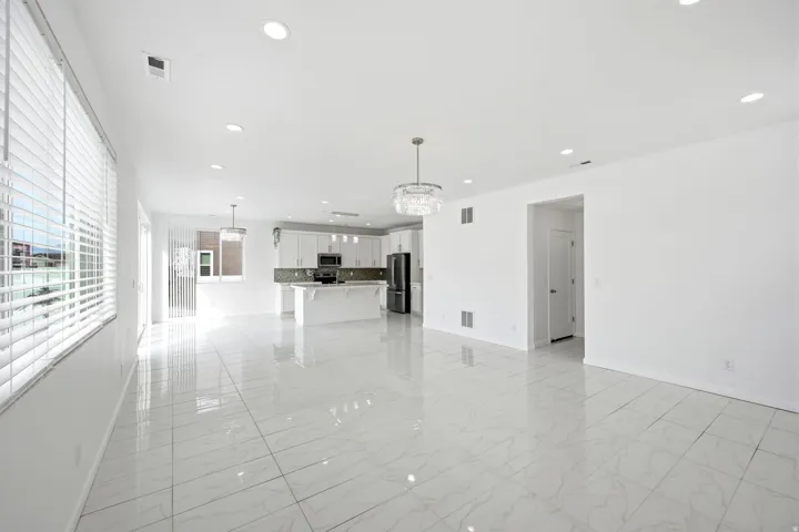 Open-concept living area with large format marble-look tile flooring, recessed lighting, and a modern chandelier