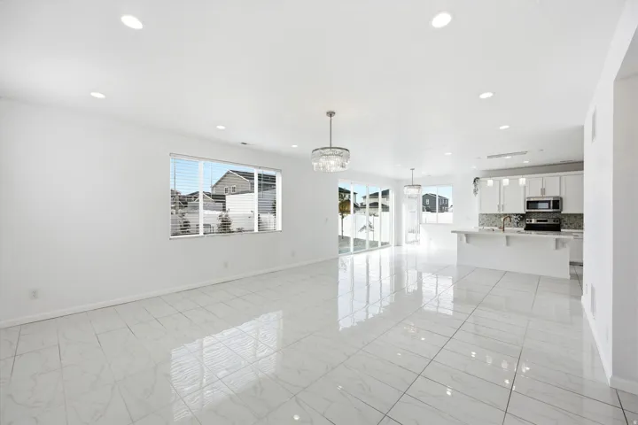 Open-concept living space featuring large format white tile flooring, recessed lighting, and a modern chandelier