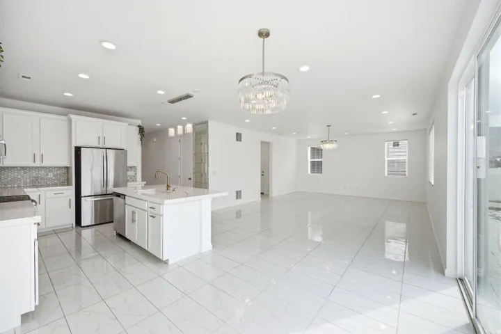 White kitchen featuring stainless steel appliances, a center island with sink, and white cabinetry