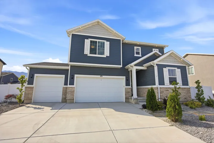 Contemporary two-story residence featuring dark blue siding, light stone-finish accents, and white trim