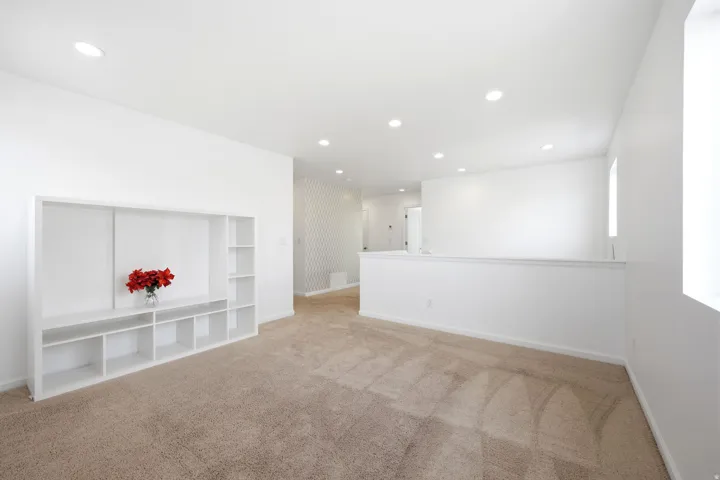 Spacious open room featuring recessed lighting, light-toned carpeting, and a built-in media console with shelving