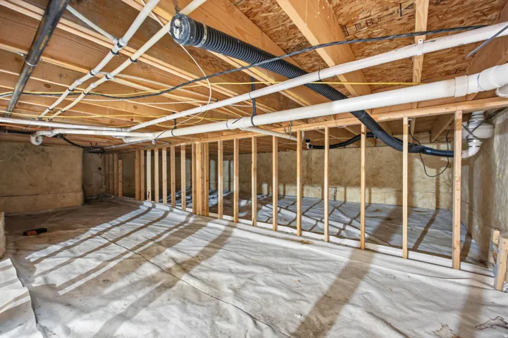 Crawl space featuring visible wooden joists, subfloor, and structural framing