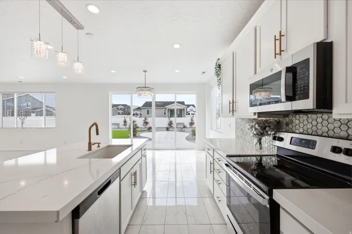 Open-concept kitchen featuring white cabinetry, quartz countertops, and stainless steel appliances
